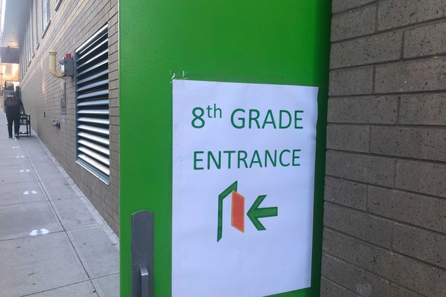 A exterior green door and a sign that says "Eighth grade"